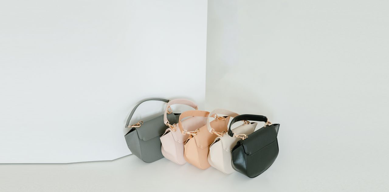 A stylish assortment of pastel handbags elegantly displayed against a minimalist backdrop in a studio setting.